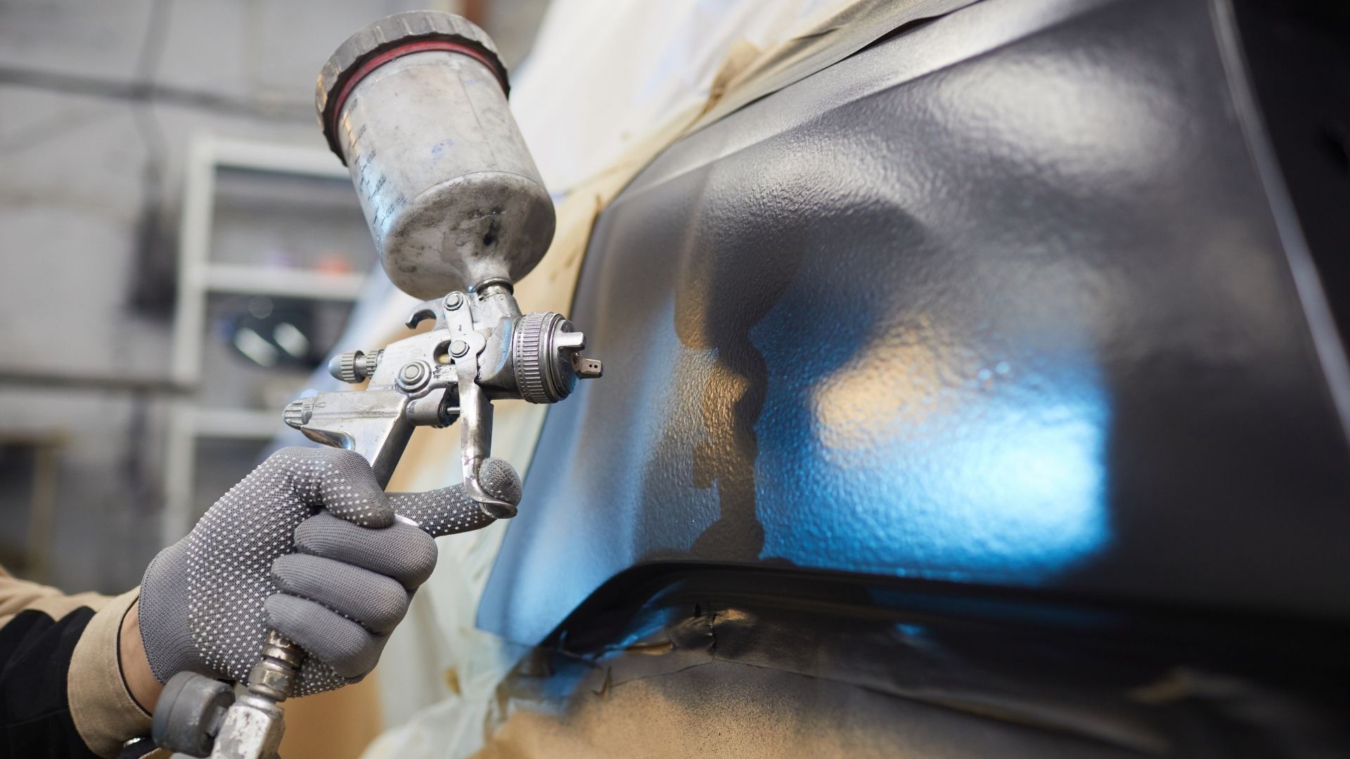 Technician repairing car dent and preparing surface for painting